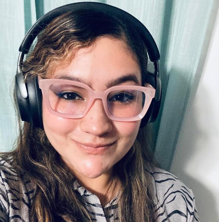 Young woman wearing headphones and stylish glasses, enjoying in-flight essentials for a first-class feeling on a coach budget.