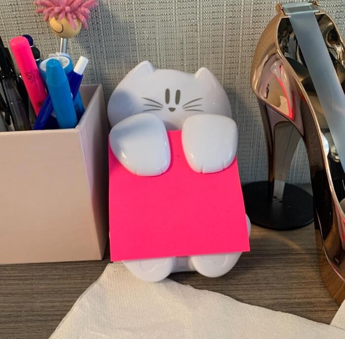 Cat-shaped memo holder on desk with colorful pens and a high-heeled shoe, enhancing your desk happy place finds.