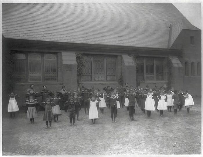 Group of African American children in early 1900s clothing standing outside a large building, captured at the Paris Exposition.