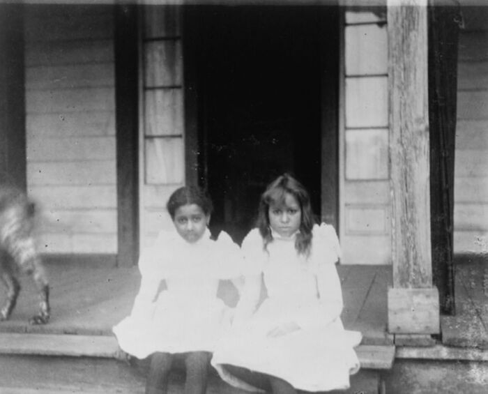 Two young girls in white dresses sitting on a wooden porch, historical African American life at 1900 Paris Exposition photo.