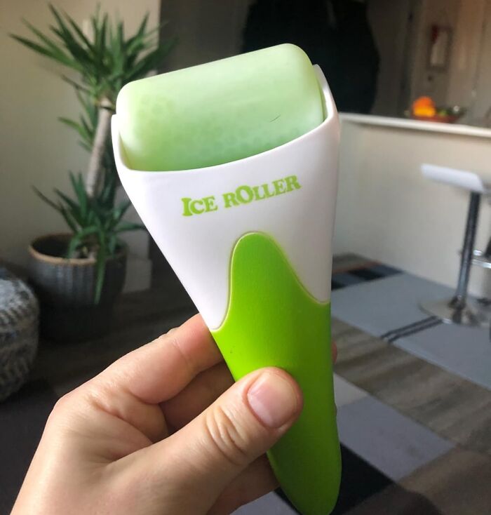 Hand holding a green and white ice roller, a tool often recommended to hack your way into becoming a morning person.