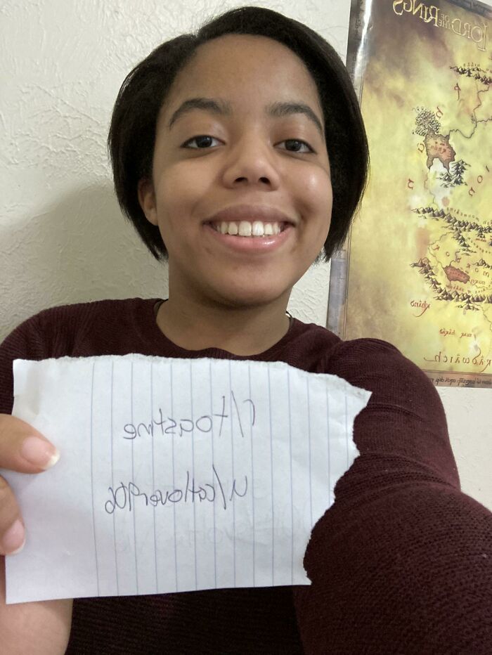 Smiling person holding a handwritten note, part of 80 people who asked the internet to toast them with kind comments.