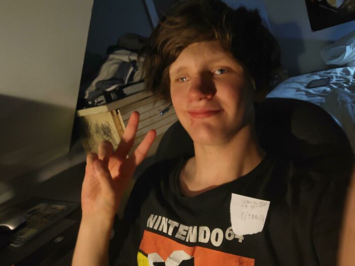 Young person smiling and posing with a peace sign after asking the internet to toast them, receiving kind comments online.