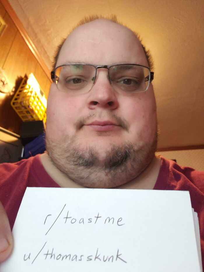 Man wearing glasses holding a toast me sign, part of people who asked the internet to toast them.