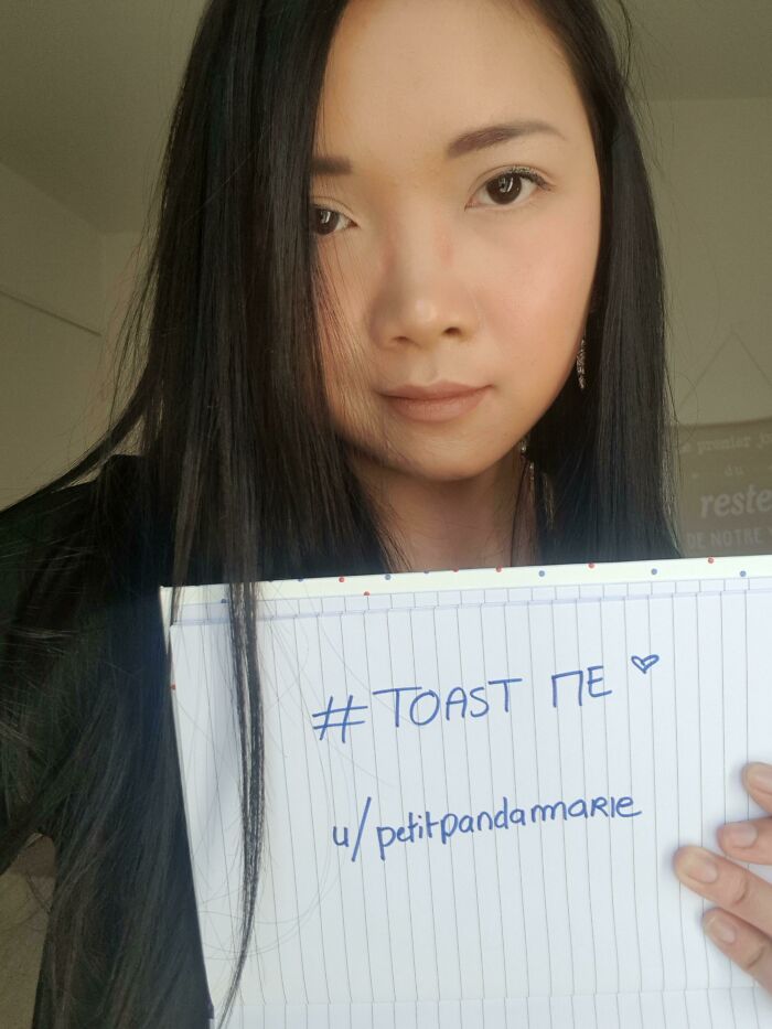 Young woman holding a notebook with hashtag toast me written, part of the internet toast people with nicest comments trend.