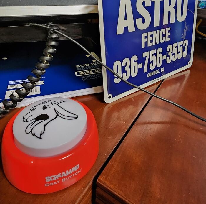 Screaming goat button on a desk next to blue Astro Fence sign and notebooks, chaotic products with unique appeal.