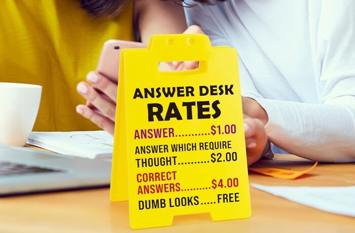 Yellow chaotic product with humorous answer desk rates and two people using phones in the background on a table.