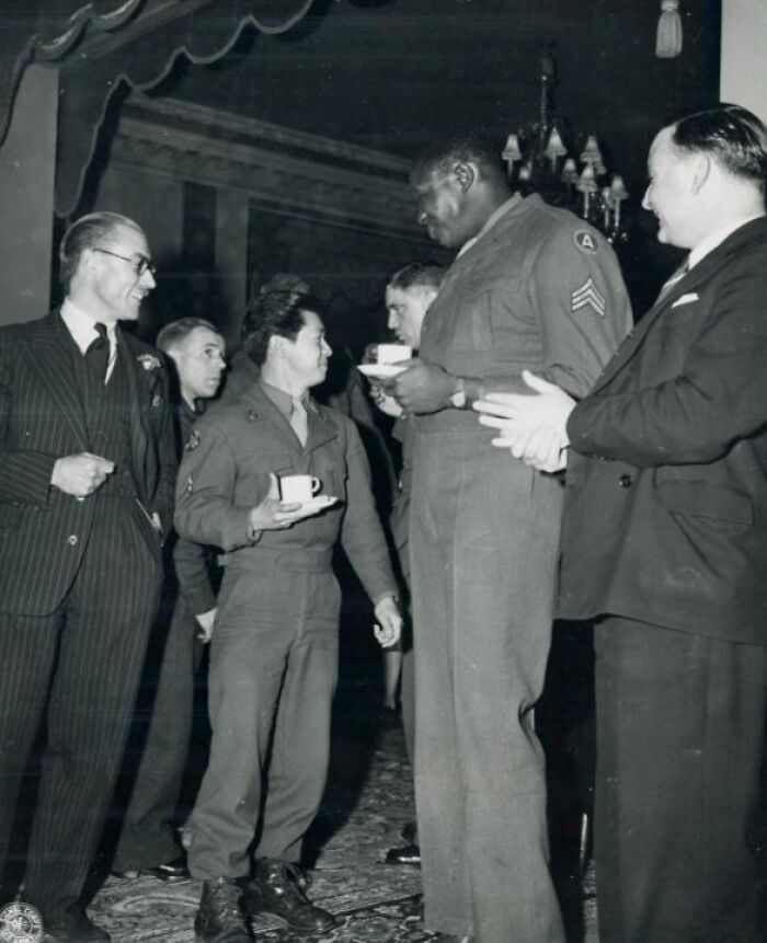 African American soldier in uniform sharing a moment with others during a historic military gathering.