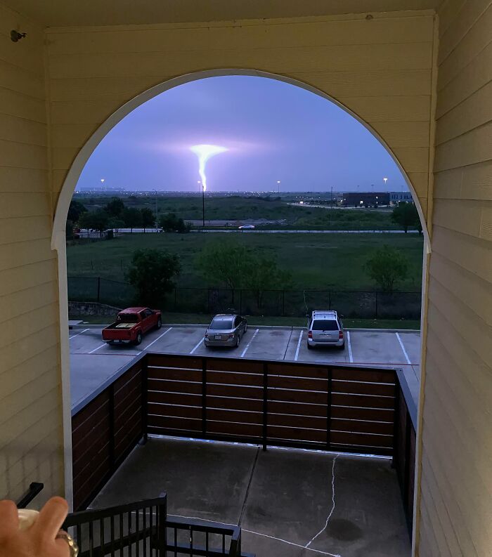 View of a lightning strike shaped like a tornado seen through an archway, showcasing one-in-a-million coincidences.