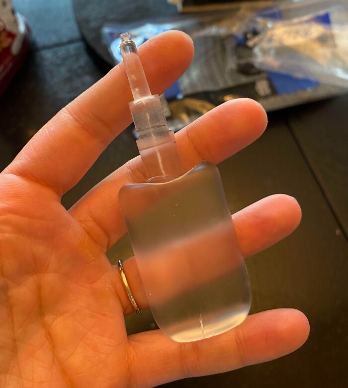 Hand holding a clear plastic object resembling a bottle top, demonstrating a one-in-a-million coincidence.