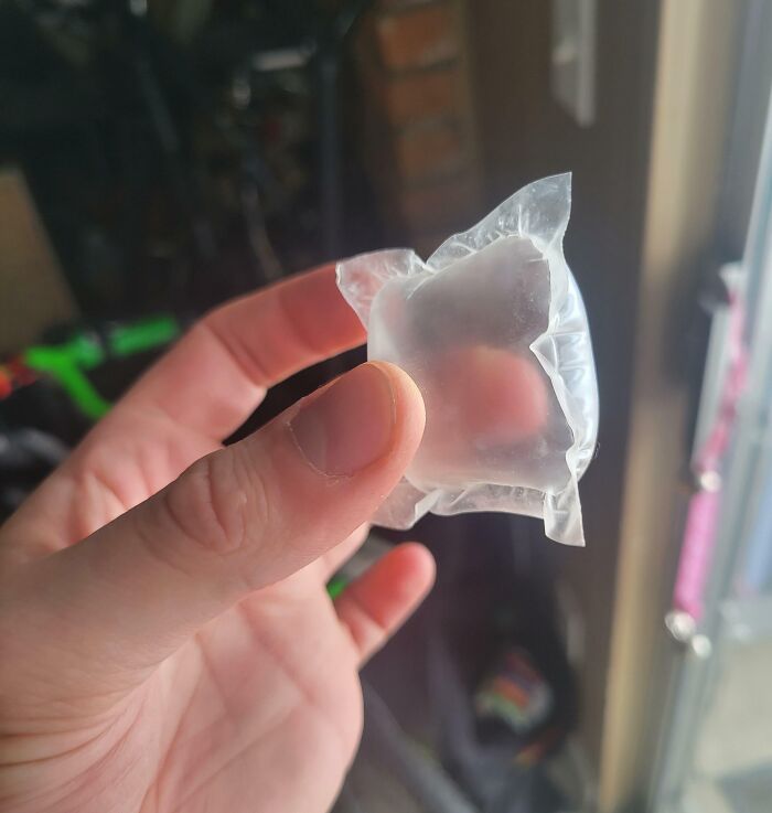 Hand holding a transparent water packet with an unusual shape, illustrating a one-in-a-million coincidence moment.