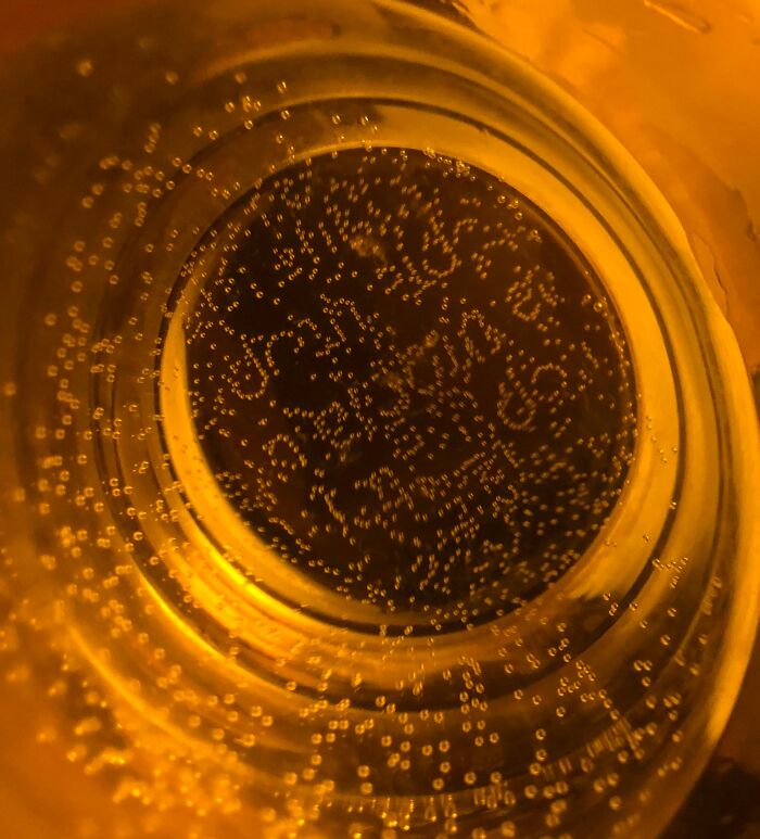 Close-up of carbonated bubbles inside a glass forming patterns resembling one-in-a-million coincidences in liquid.