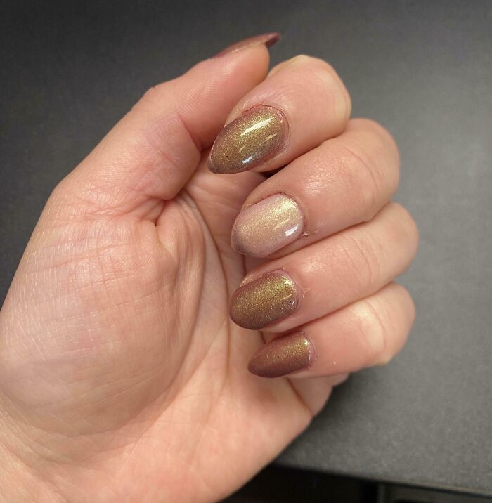 Close-up of a hand with shiny, metallic nail polish showing a one-in-a-million coincidence in nail art.
