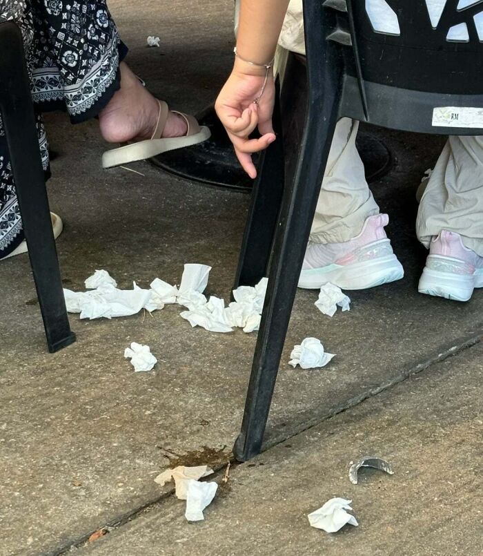 Littered trash and tissues under chairs showing rude and obnoxious tourists behaving disrespectfully in a public area.