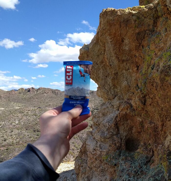 Hand holding a Clif Bar in front of a rocky cliff in a desert landscape illustrating one-in-a-million coincidences.