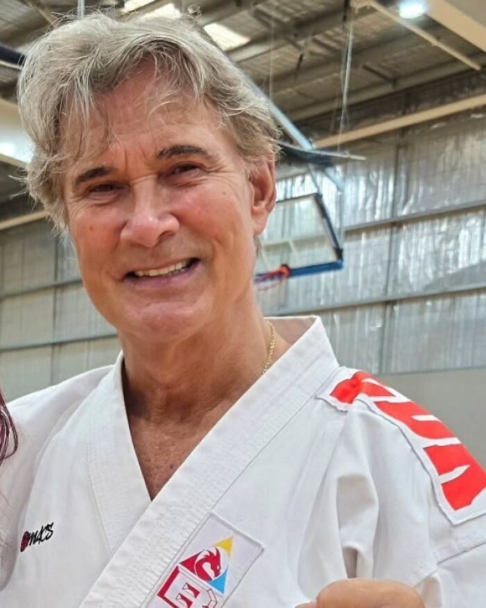 Smiling man in martial arts uniform inside a gym, representing notable people who passed away in 2025.