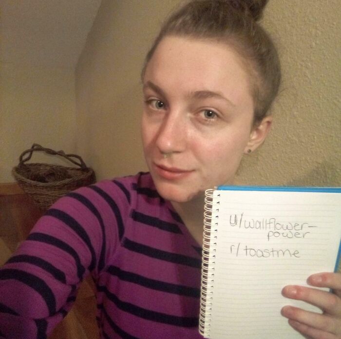 Young woman in a purple striped sweater holding a notebook, participating in an internet toast and nice comments thread.