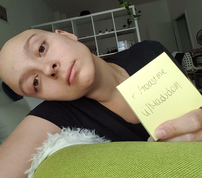 Person with shaved head holding a note requesting internet toast, part of 80 people who asked for toast online.
