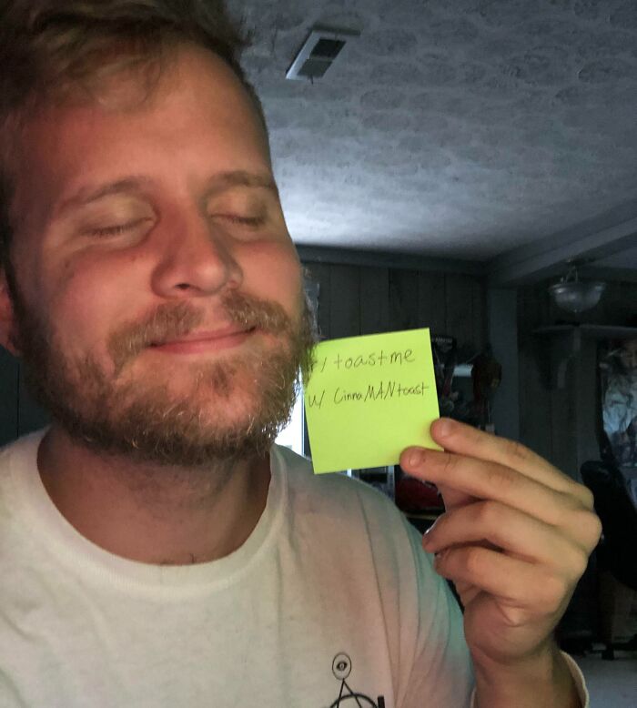 Man smiling with eyes closed holding a note for internet toast requests, showcasing positive comments from online community.