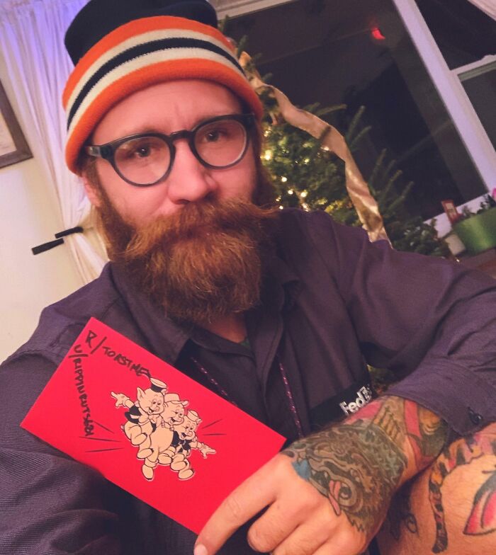 Bearded man wearing glasses and a striped hat holding a red card from a popular internet toast community.