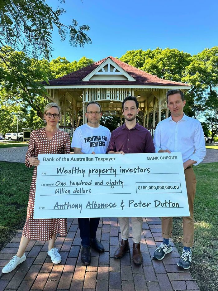 Four people standing outdoors holding a large check highlighting wealthy property investors in bad landlords renting issues.