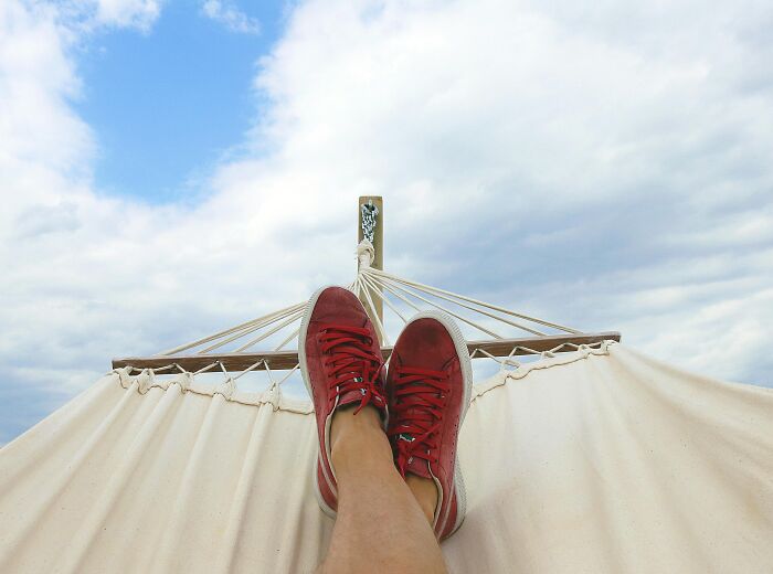 Person wearing red sneakers relaxing on a hammock under a cloudy sky, reflecting on harsh life lemons advice.