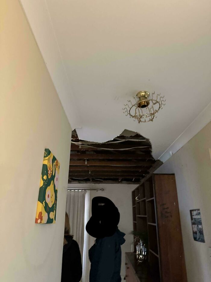 Ceiling collapsed in a rental property with exposed wooden beams and broken plaster, showing bad landlords neglecting repairs.