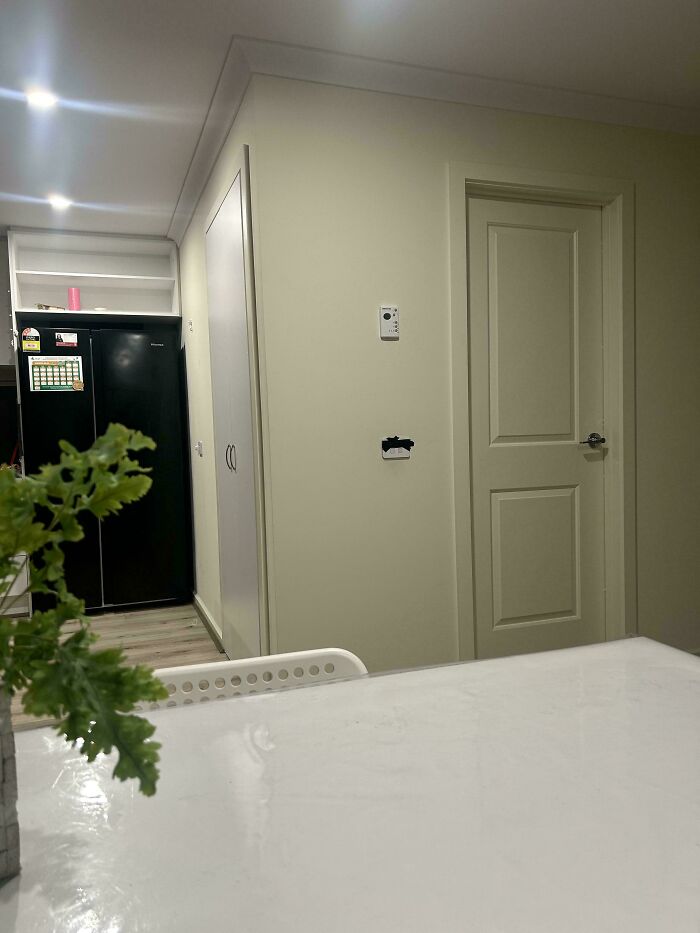 Interior of rental room showing closed doors, black refrigerator, and minimal decoration in a space reflecting bad landlords' poor upkeep.