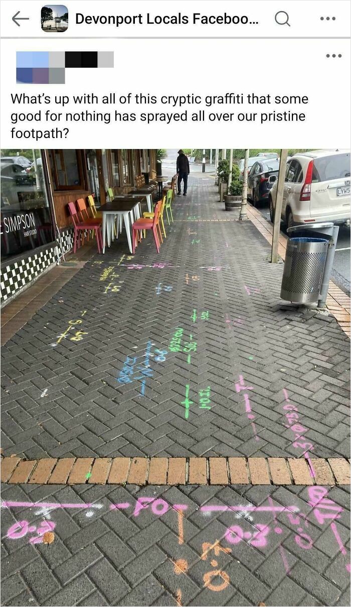 Footpath covered in colorful chalk graffiti resembling complex bacteria-like diagrams, confusing passersby and locals.
