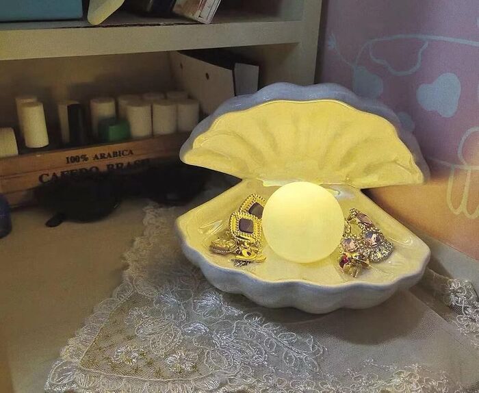 Decorative clam shell jewelry holder with glowing orb and assorted rings, showcasing Amazon hidden gems collection.
