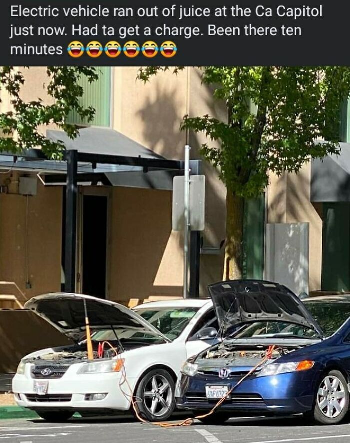 Two cars with open hoods in a parking lot connected by jumper cables, illustrating a misunderstanding about electric vehicle charging.