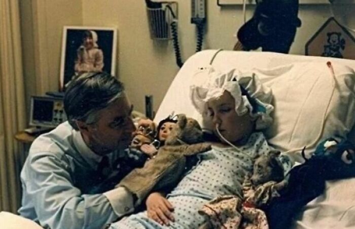 Doctor using puppets to comfort a child patient in a hospital bed in a vintage photo showing history up close.