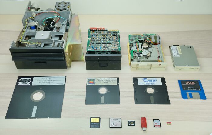 Various computer storage devices from floppy disks to modern USB drives arranged on a table showing before and after technology changes.