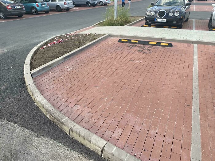 Parking space with dangerous curved curb design that could be classified as a death trap for vehicles and pedestrians.