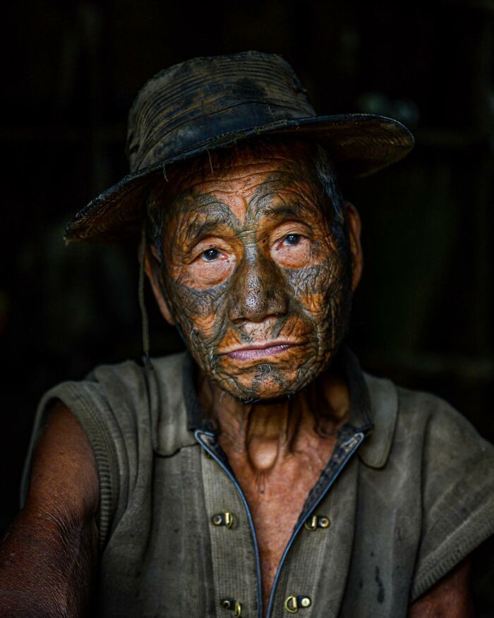 Elderly man with traditional facial tattoos wearing a hat, captured in a striking portrait of elderly people across the globe.