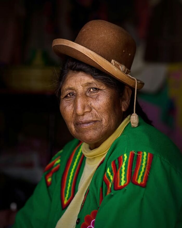 Elderly woman wearing traditional clothing and a hat, captured in a striking portrait showcasing diverse faces across the globe.