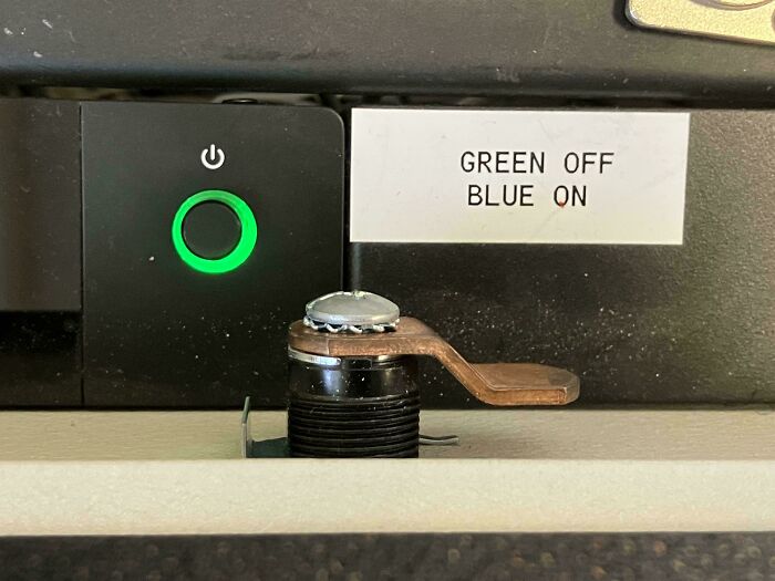 Power switch with a green light next to a label incorrectly stating green off and blue on, an example of dangerous design.