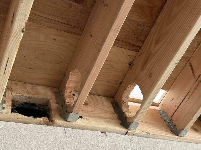 Wooden ceiling beams with large holes cut out, showcasing a dangerous design that could be classified as a death trap.