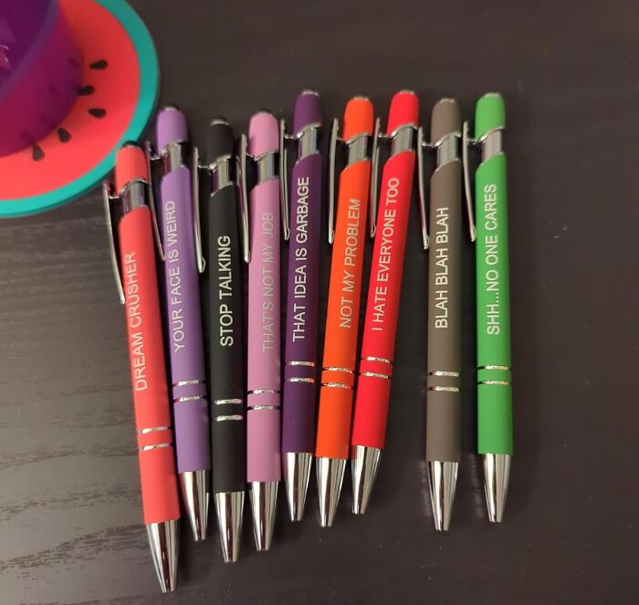 Colorful bestselling pens with humorous phrases displayed on a dark surface, popular among pandas and stationery fans.