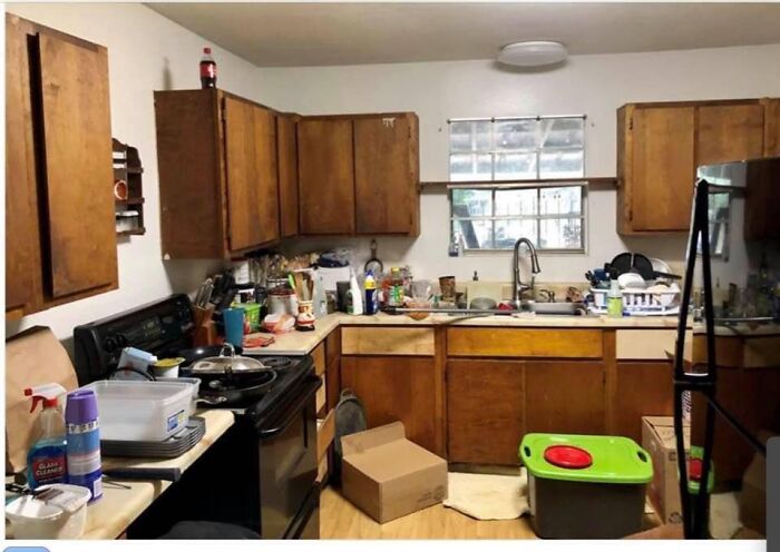 Cluttered and messy kitchen with wooden cabinets and boxes, illustrating worst real estate photos for home listings.