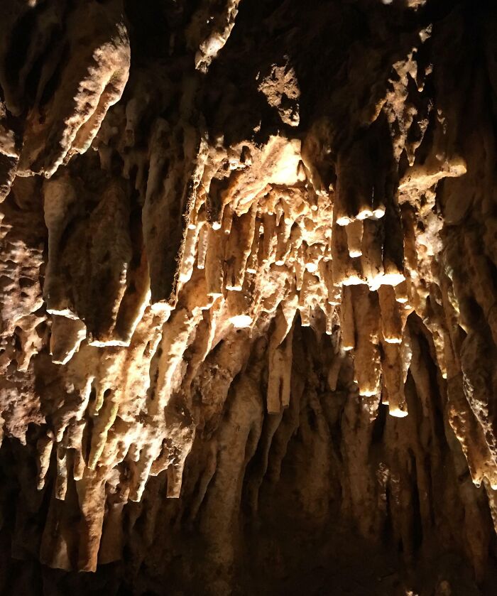 Stalactites inside a dimly lit cave, with natural rock formations creating a dramatic underground scene.