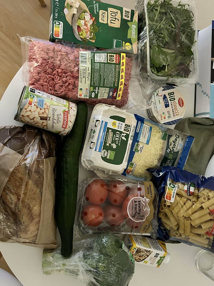 Grocery haul featuring fresh produce, eggs, tofu, pasta, and dairy products showing grocery cost where they live.