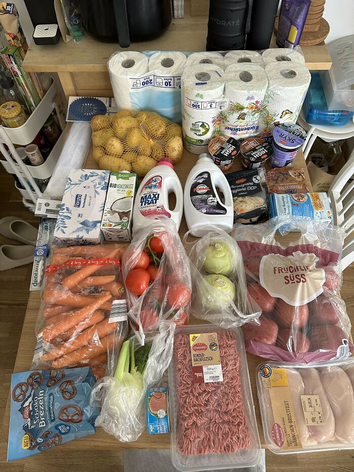 Various groceries including vegetables, meat, dairy, and essentials displayed on a table showing grocery costs.
