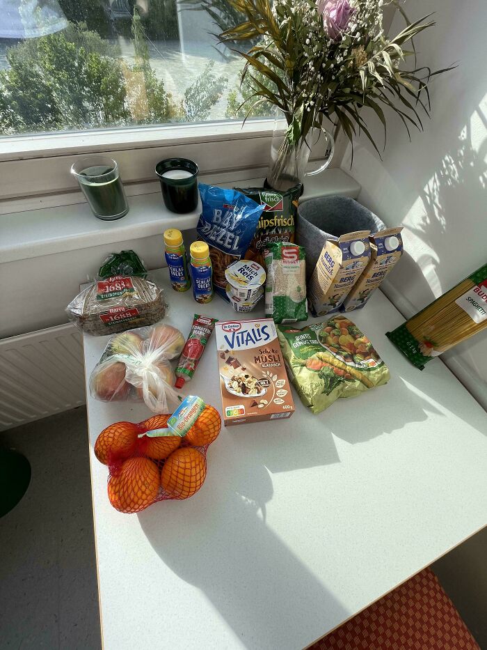 Groceries including bread, fruits, cereal, dairy, and snacks displayed on table showing grocery costs where they live.