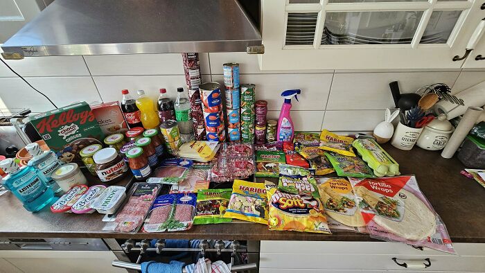Groceries laid out on kitchen counter showing variety and cost for 80 people sharing how much groceries cost where they live