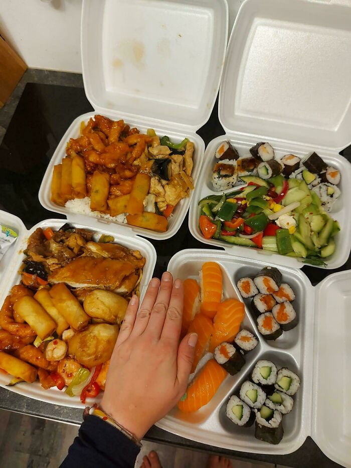 Four takeout containers with Chinese and sushi meals showing grocery cost comparison with a hand for size reference.