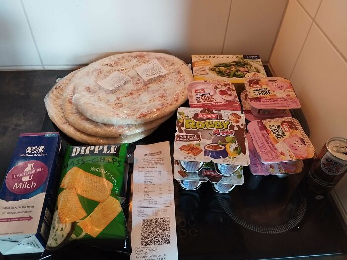 Groceries including frozen pizzas, chips, milk, yogurt, and canned drink showing cost where they live.