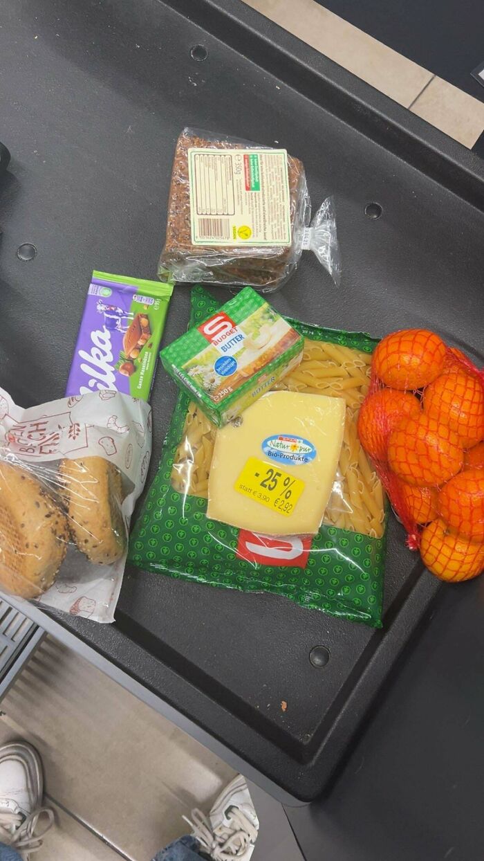 Grocery items including bread, pasta, cheese, butter, chocolate, and oranges displayed to show grocery cost.