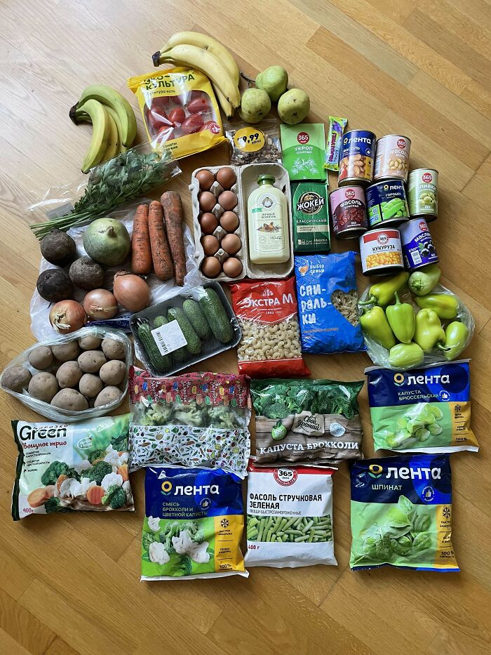 A variety of groceries including fresh vegetables, canned goods, eggs, and packaged foods showing grocery cost differences.