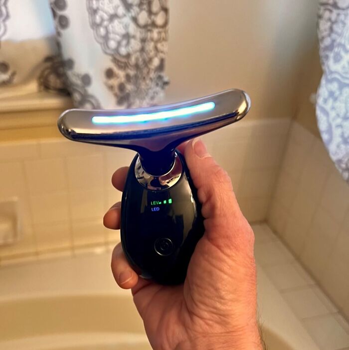 Hand holding an internet gold product on Amazon with glowing LED light in a bathroom setting.